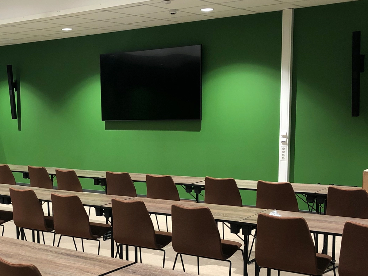 Modernt konferensrum med stor skärm, kamera, mikrofon och styrpanel